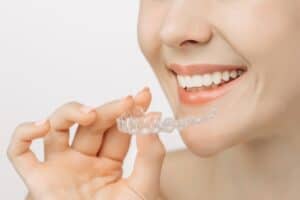 A close-up shot of a woman holding an Invisalign aligner
