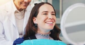 Woman looking in the mirror after laser dentistry appointment